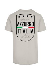 Light gray T-shirt featuring a black shield design with text "Orgoglio Azzurro IT AL IA nel Cuore" and Italian flag colors. Five stars above.