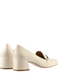 Krämfärgade patenterade läderloafers med låg klack, rund tå och dekorativ metalldetalj på ovandelen. Slät, glänsande yta.