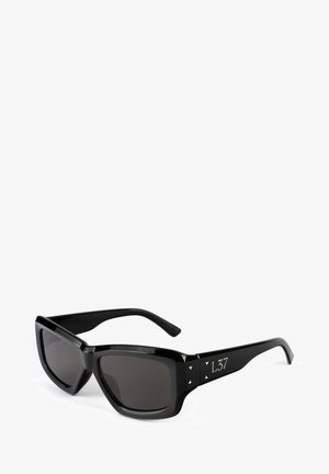 Mustat aurinkolasit suorakulmaisen kehykset, tummat linssit ja kolmionmuotoiset korostukset sivuilla. Sujuva muovipinta, moderni muotoilu.