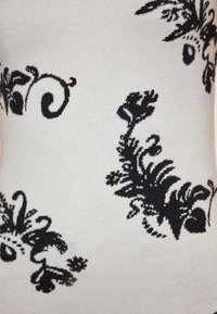 Motivo floreale nero su un tessuto grigio chiaro testurizzato, con disegni intricati e forme varie che attraversano la superficie.