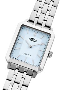 Strieborné obdĺžnikové quartz hodinky so svetlomodrým ciferníkom, striebornými hodinovými ukazovateľmi a nerezovým remienkom z článkov. Obsahuje korunku na boku.
