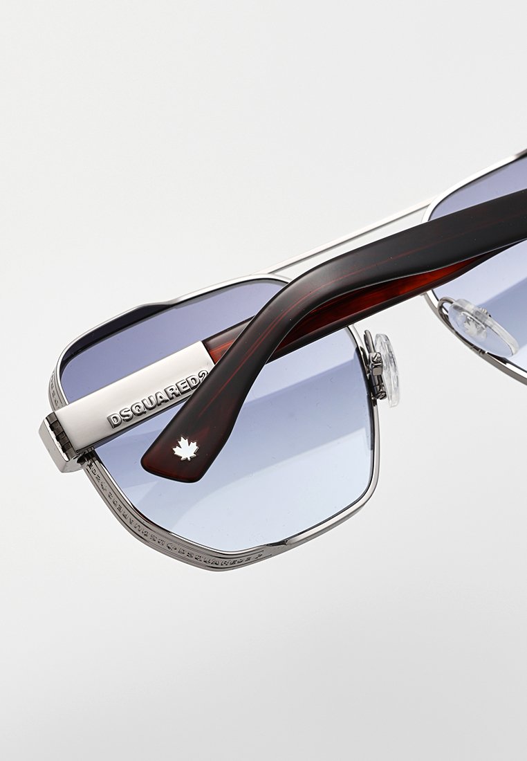 Hexagonala solglasögon med graduerade blå linser, silvermetallramar och tempelarmar i brunt acetat med ett detalj av en lönnlöv.