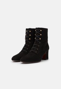 Stivaletti neri in suede alla caviglia con punta appuntita, lacci sul davanti con hardware dorato e tacco a blocco. Texture liscia con un design classico.