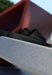 Black slide sandals with a textured upper, featuring a low profile and molded footbed. The brand "LIGHTSTRIKE" is embossed on the side.