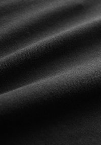 Tissu noir avec une texture fine en maille visible et des plis doux créant des ombres et des jeux de lumière.