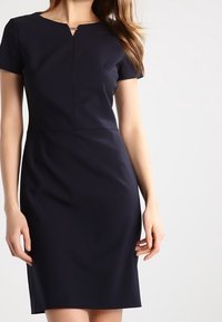 Robe bleu marine à manches courtes avec une silhouette ajustée, un détail d'encolure goutte d'eau et une texture de tissu lisse. Design longueur genou.