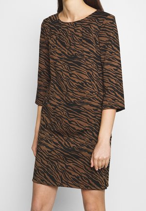 Kvinde iført en brun og sort kjole med tigerstriber, trekvartærmer og rund halsudskæring.