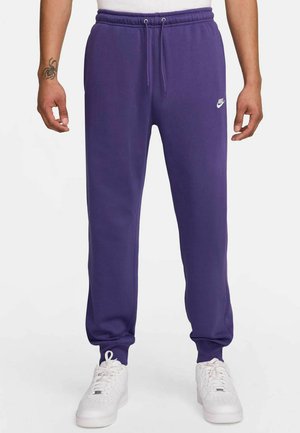 Purple sweatpants made of soft fabric, featuring an elastic waistband with drawstrings and a small white Nike logo on the left thigh.