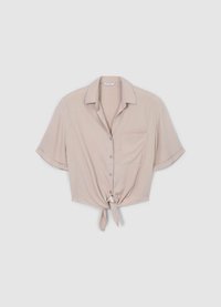 Chemise beige clair à manches courtes avec fermeture à boutons sur le devant, lien au bas et une poche poitrine unique. Tissu lisse avec un léger éclat.
