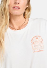 Weißes T-Shirt mit einem zentrierten pinken Grafikdesign mit stilisierten Sonnen und Wellen. Rundhalsausschnitt, weicher Stoff und entspannte Passform.