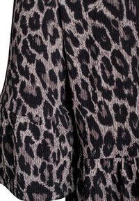 Robe imprimée léopard avec une texture côtelée, couleurs noire et beige, manches évasées et détail de basques.
