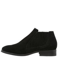 Black suede ankle boots featuring a smooth finish, elastic side panels, and a low, stacked heel. The design includes subtle ribbed accents.