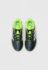 Zwarte voetbalschoenen met neon groene accenten, witte strepen en zwarte veters. Strak ontwerp met een gladde textuur en een flexibele zool.