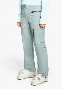 Schneehosen in hellem Türkis, aus wasserdichtem Material, verfügen über zwei Reißverschlusstaschen, einen hohen Bund und einen lockeren Schnitt.