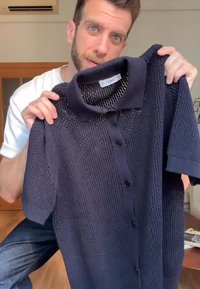 Polo a maniche corte di colore blu navy realizzato in tessuto a maglia testurizzato, con bottoni sulla parte frontale e un design classico del colletto.