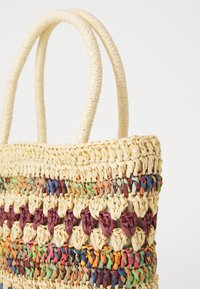 Bolso de paja trenzada con acentos coloridos y naturales. Presenta dos asas texturizadas y una abertura espaciosa.