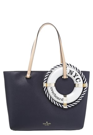 Granatowa torba typu tote z beżowymi uchwytami, ozdobiona białą ozdobą w kształcie koła ratunkowego z napisem "NYC" i "overboard" na przodzie.