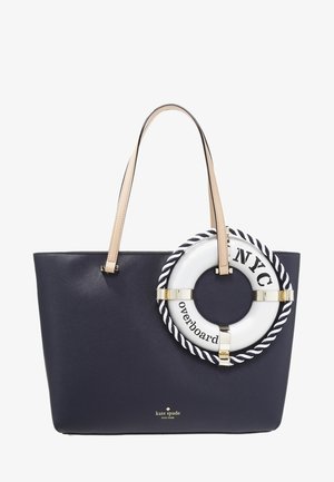 Granatowa torba typu tote z beżowymi uchwytami, ozdobiona białą ozdobą w kształcie koła ratunkowego z napisem "NYC" i "overboard" na przodzie.