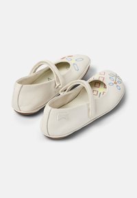 Bailarinas de cuero blanco con punta redonda y una correa. Presentan coloridos patrones bordados y un pequeño logo en la parte trasera.