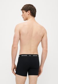 Mustad puuvillased bokserid laia elastse vöökohaga, millel on "ONLY&SONS" logo; sile tekstuur ja vormis disain, tagantvaade.
