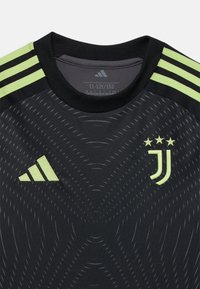 Maillot noir de la Juventus avec des rayures vertes Adidas, présentant un motif texturé et le logo du club avec trois étoiles, un col rond et des manches courtes.