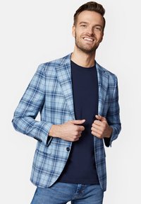 Jasnoniebieski blazer w kratę, wykonany z tkaniny o gładkiej teksturze, o dopasowanym kroju, z klapami i dwoma guzikami. Pod spodem casualowa granatowa koszula.