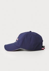 Marineblå baseballkasket med en buet skygge, prydet med et broderet logo og et lille amerikansk flag. Tekstureret stof med justerbar stropdetalje.