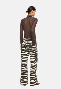 Czarna, przezroczysta bluzka z długim rękawem zestawiona z szerokimi spodniami w zebrę w czarno-białym kolorze, posiadającymi kieszenie i luźny krój.
