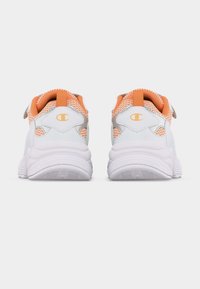 Paire de chaussures de sport blanches et orange avec des semelles épaisses vues de dos, avec un logo sur les languettes du talon.