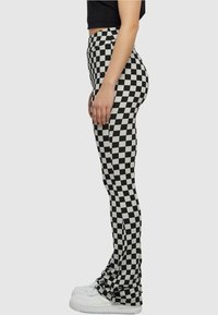 Schwarz-weiße karierte Leggings mit hoher Taille, aus dehnbarem Material, mit einer figurbetonten Silhouette.