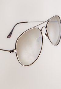 Metal aviator sunglasses with reflective lenses, thin silver frames, and tortoiseshell-patterned arms. Features adjustable nose pads.