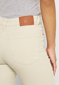 Beige kordflorbyxor med en läderetikett från BDG, med en åtsittande design, bakfickor och en strukturerad yta.