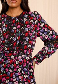 Schwarzes Blumenkleid mit roten, violetten und rosa Blumen, Spitzenverzierungen, langen Ärmeln, einer taillierten Taille und einem plissierten Rock.