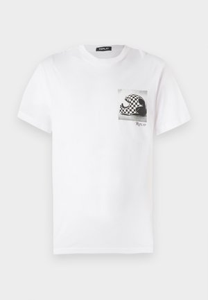 T-shirt bianca in cotone con una grafica in bianco e nero di un'onda con un motivo a scacchi sulla tasca del petto. Vestibilità morbida e colletto rotondo.