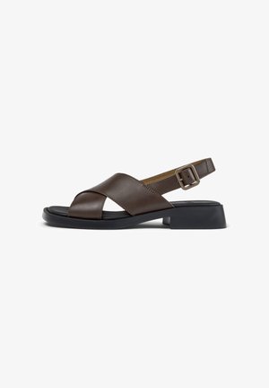 Brown leather sandal with crisscross straps, adjustable buckle, black cushioned sole, and low block heel.