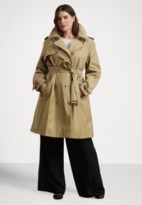 Bézs színű ballonkabát dupla soros gombolással, derékrészen övvel és túlméretezett gallérral. Arany színű fém részletekkel és mandzsetta dizájnnal rendelkezik.