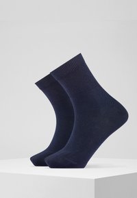 Calcetas azul marino hechas de un material suave, con un puño acanalado. El diseño es de altura a los tobillos, con una textura lisa y punta redondeada.