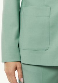 Light green tailored blazer sleeve featuring a square patch pocket, smooth texture, and clean stitching without visible hardware or accents.