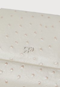 Cream leather wallet with embossed dot texture and subtle sheen. Features a raised logo in the bottom corner. Elegant and sleek design.