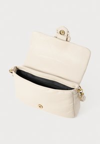 Leather handbag in light cream with a gold-tone snap closure. Interior features a black lining and a zippered pocket for organization.