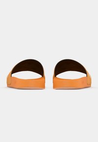 Πορτοκαλί σανδάλια με μινιμαλιστικό σχέδιο, με ανοιχτό δάχτυλο, κυρτές άκρες και υφή στην σόλα για καλύτερη πρόσφυση. Λείο υλικό στο επάνω μέρος.