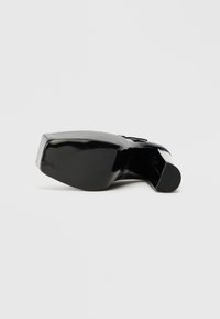 Zapato de tacón alto de charol negro con punta redondeada y suela texturizada. Presenta un tacón cuadrado y una superficie lisa y elegante.