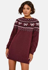Abito maglione bordeaux in un morbido filato, caratterizzato da un motivo Fair Isle con fiocchi bianchi e forme geometriche lungo lo scollo e le maniche.