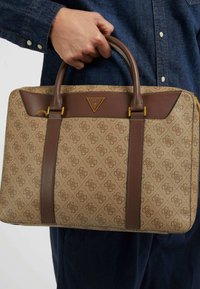 Braune und beige gemusterte Ledertasche mit zwei oberen Griffen, goldenen Beschlägen und einem dreieckigen Logo-Akzent; rechteckige Form, strukturiertes Design.
