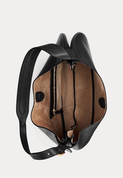 Sac cabas en cuir noir avec une large bandoulière, ouverture supérieure montrant un intérieur en daim beige, une poche zippée et deux compartiments ouverts à l'intérieur.