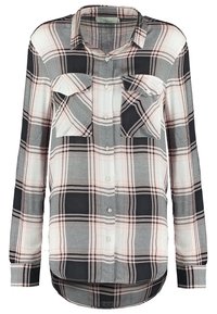 Chemise à manches longues à carreaux avec des couleurs noir, gris et rose. Dotée de deux poches poitrine et d'un ourlet incurvé. Confectionnée en tissu léger.