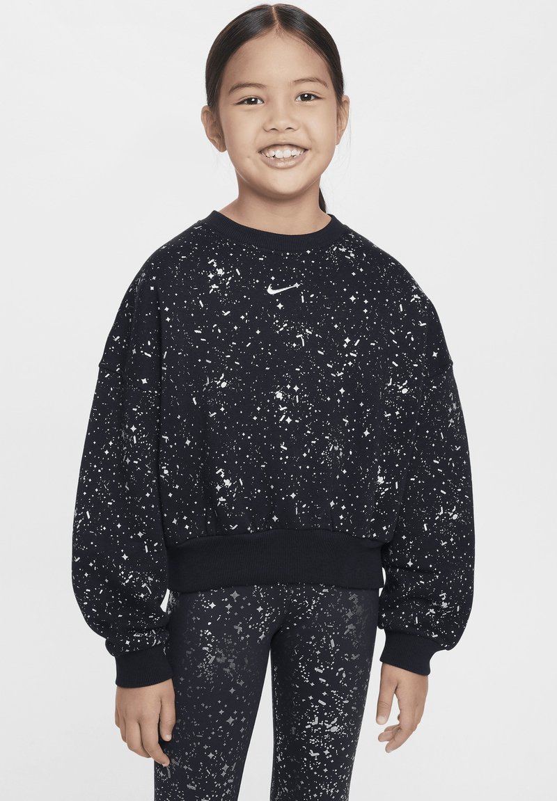 Felpa nera in pile con motivo a macchie bianche, con polsini e orlo a coste, caratterizzata da un piccolo logo bianco sul petto. Indossata con leggings abbinati.