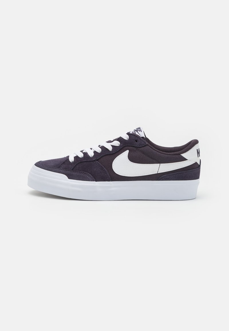 Nike-tennarit, joissa on tummanvioletti mokkanahkainen päällinen, valkoiset nauhat ja iso valkoinen Swoosh-logo sivussa. Valkoinen kumipohja.