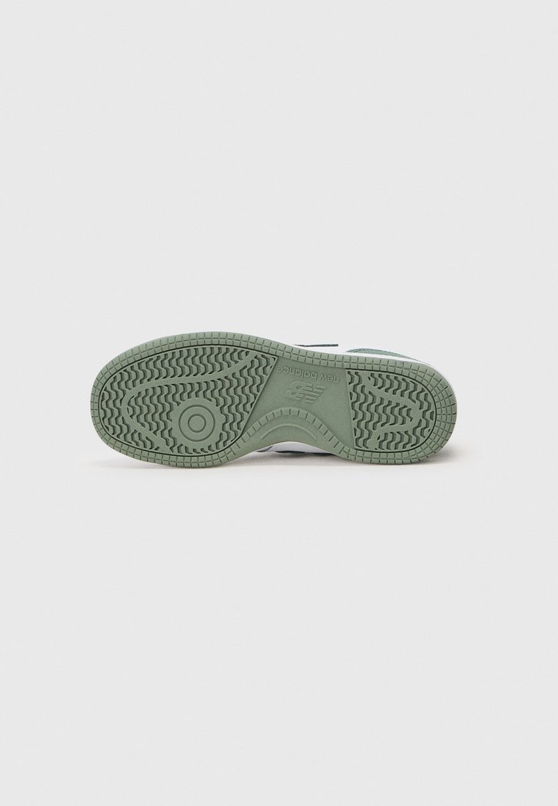Suela de caucho verde con un patrón de relieve texturizado, forma redondeada y acentos laterales blancos. Áreas reforzadas para una mayor durabilidad.