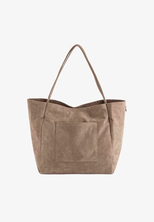 Grand sac fourre-tout en suede beige avec deux longues poignées et une poche avant. Le design a une texture douce et un dessus ouvert.